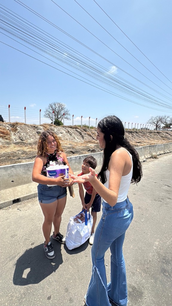 Voluntarios entregando suministros a familia en la calle, con sonrisas.
