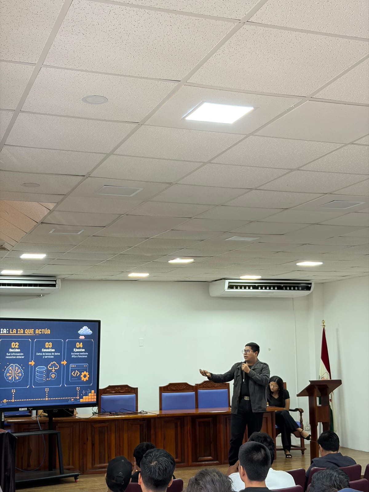 Josue Castro presenting a talk on agentic AI in a university auditorium
