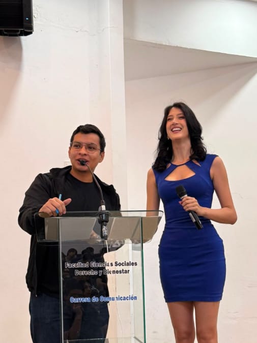 Luis Figueroa co-hosting on stage at the Carrera de Comunicación podium